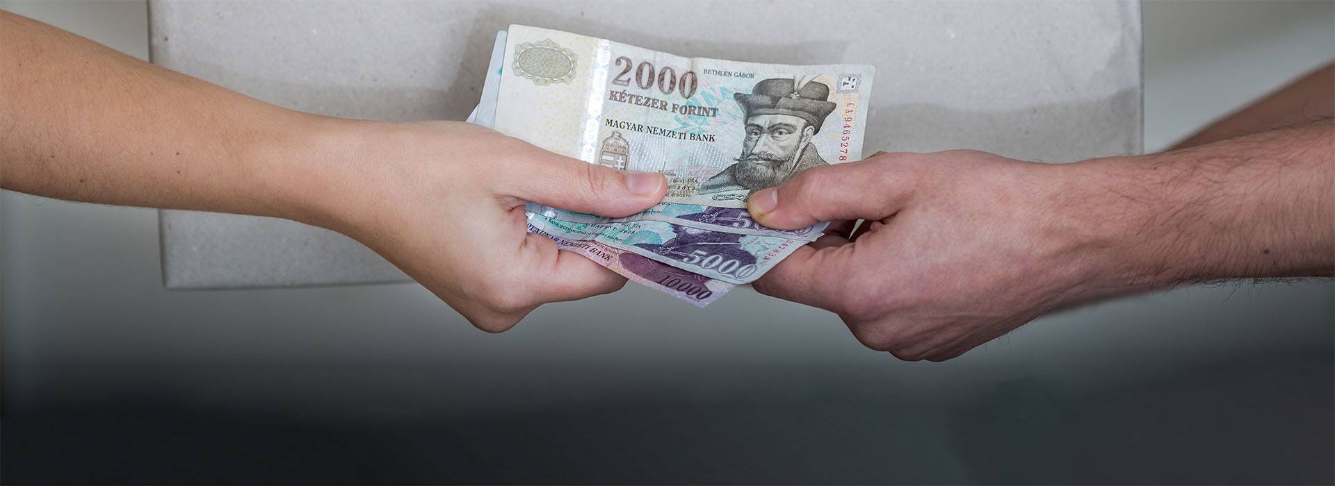 A képen egy csomag és egy bankjegyeket átnyújtó kéz látható.