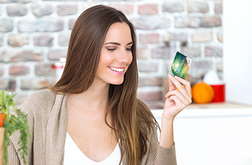 A képen egy mosolygós hölgy látható, aki a kezében egy ÉnPostám kártyát tart.