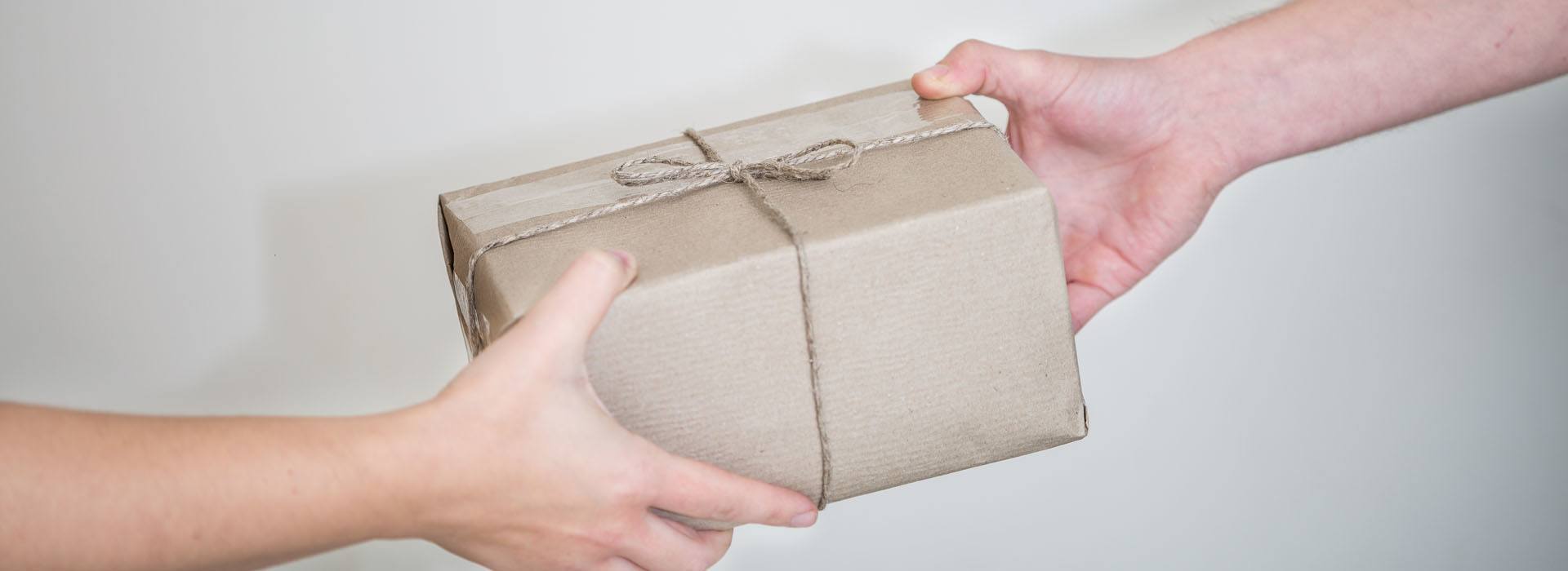 A képen egy csomagot átadó és egy csomagot átvevő kéz látható.