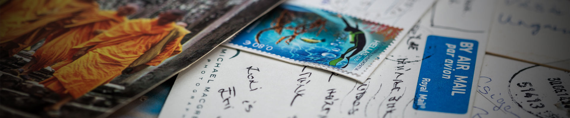 A képen egy angol légiposta címke, egy búvárt ábrázoló bélyeg és egy buddhista szerzetest ábrázoló képeslap látható.