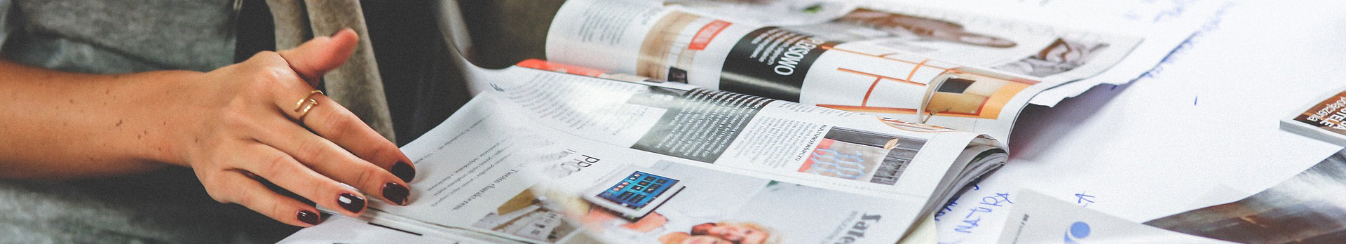 A képen egy hölgy lapozgat egy magazint.